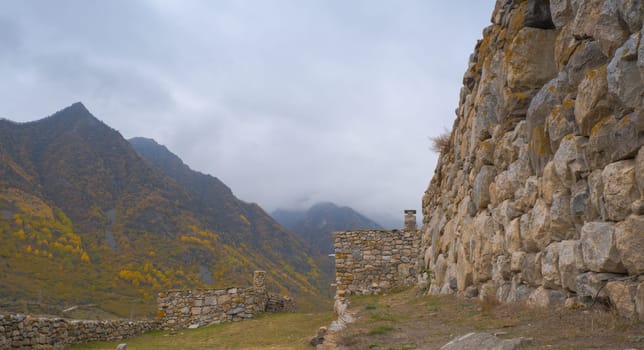 Seasonal autumn landscape in the Caucasus Mountains of Russia. Cloudy day with yellow trees and mountains behind. Popular travel destination in autumn.