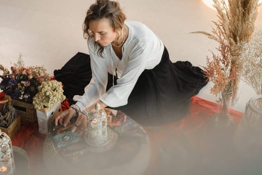 Women's circle and practice in the use of metaphorical cards. The girl is sitting surrounded by flowers.