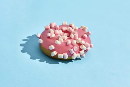Food design. Close up high quality image of sweet tasty pink glazed donut on blue background. Mock up, flat lay