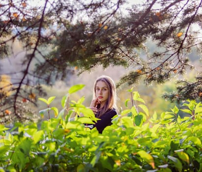 Beautiful girl in green foliage in the autumn park