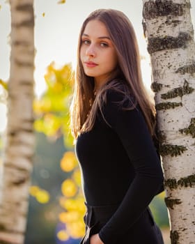 A beautiful girl posing near a birch tree in an autumn park