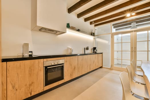 a kitchen and dining area in a modern apartment with white walls, wood flooring and black countertops