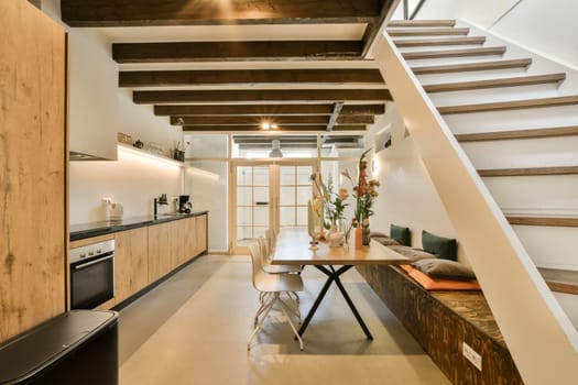 a kitchen and dining area in a loft style apartment with wooden stairs leading up to the second floor, as well as it is