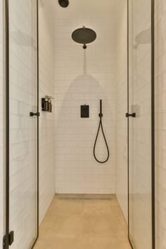 a walk in shower that is white and has black fixtures on the wall, along with an open shower door