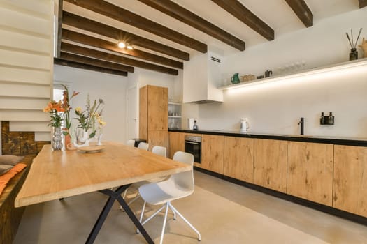 a kitchen and dining area in a house with wood beams on the ceiling, white walls and wooden flooring