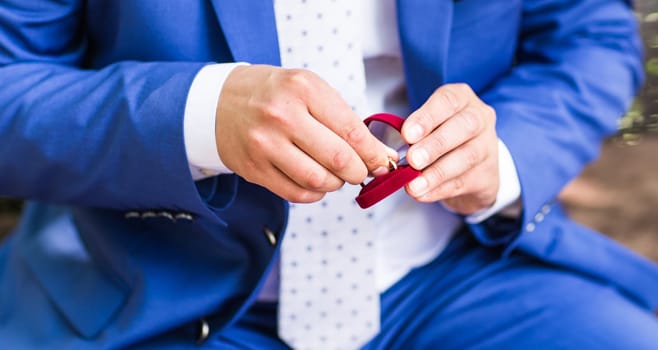 Man's hand holding engagement ring. Wedding rings