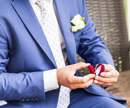 Man's hand holding engagement ring. Wedding rings