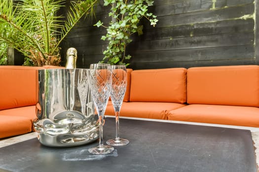 two wine glasses on a table with an orange couch in the photo is taken to the right, and it's not clear