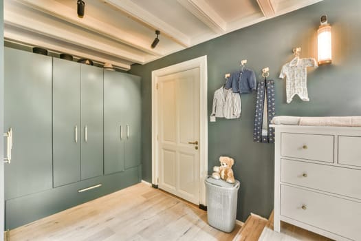 a baby's room with clothes hanging on the wall and an open door leading to another room in it