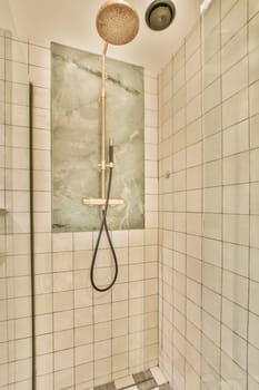 a shower in a bathroom with white tiles on the walls, and a black shower head mounted to the wall