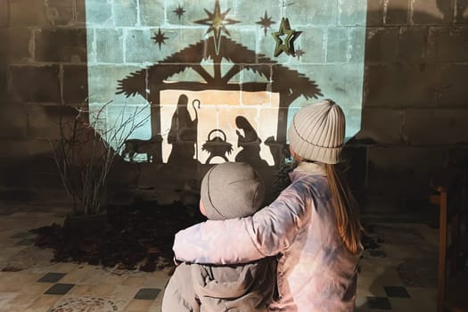 Children look at christmas creche with Joseph Mary and small Jesus