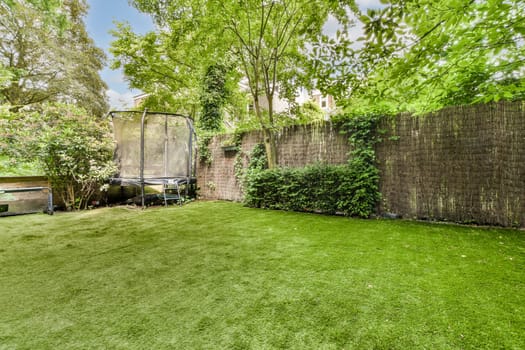 a backyard area with a fence and some green grass in the yard is surrounded by trees, shrubs and bushes