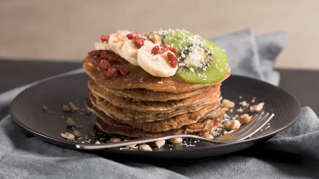 Healthy breakfast table,  homemade pancakes with kiwi, banana, goji and walnuts.