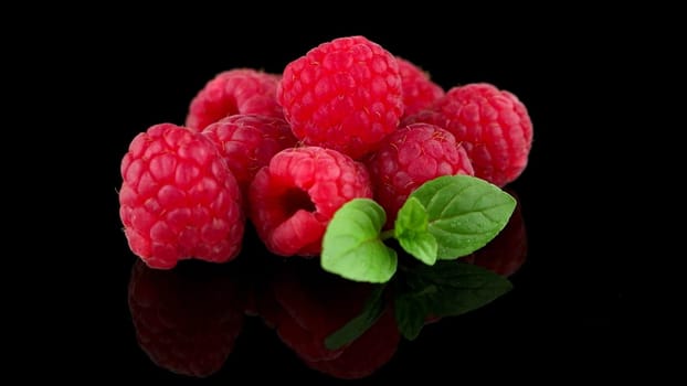 Raspberries with leaves isolated on black background