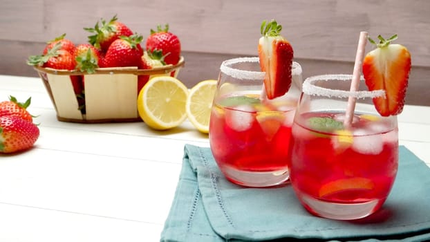 Cold strawberry drink with fresh strawberries and lemon on wooden background