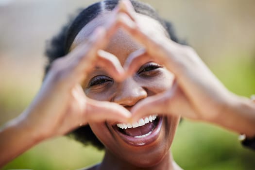 Happy black woman, portrait and face with heart hands for love, care or healthy wellness in nature. African female person smile with like emoji, symbol or icon and hand gesture for romance outdoors.
