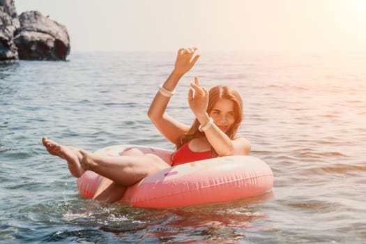 Woman summer sea. Happy woman swimming with inflatable donut on the beach in summer sunny day, surrounded by volcanic mountains. Summer vacation concept