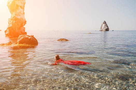 Woman travel sea. Happy tourist taking picture outdoors for memories. Woman traveler looks at the edge of the cliff on the sea bay of mountains, sharing travel adventure journey.