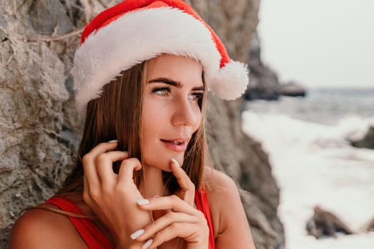 Woman travel sea. Young Happy woman in a long red dress posing on a beach near the sea on background of volcanic rocks, like in Iceland, sharing travel adventure journey