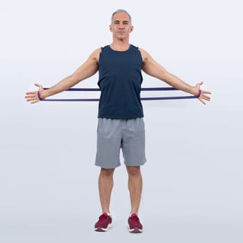 Full body length shot athletic and sporty senior man with fitness resistance band on isolated background. Healthy active physique and body care lifestyle after retirement. Clout