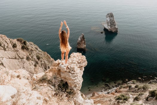 Woman travel sea. Happy tourist taking picture outdoors for memories. Woman traveler looks at the edge of the cliff on the sea bay of mountains, sharing travel adventure journey.