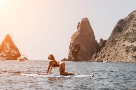 Close up shot of beautiful young caucasian woman with black hair and freckles looking at camera and smiling. Cute woman portrait in a pink bikini posing on a volcanic rock high above the sea