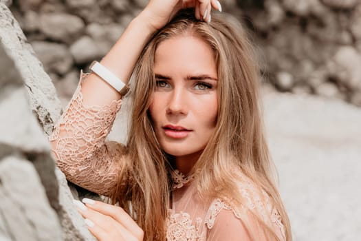 Woman travel sea. Young Happy woman in a long red dress posing on a beach near the sea on background of volcanic rocks, like in Iceland, sharing travel adventure journey