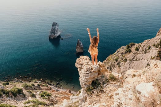 Woman travel sea. Happy tourist taking picture outdoors for memories. Woman traveler looks at the edge of the cliff on the sea bay of mountains, sharing travel adventure journey.