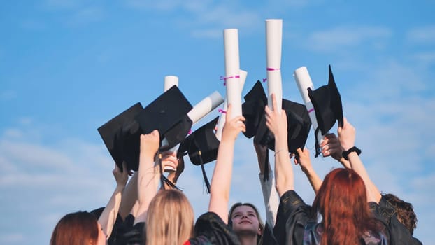 College graduates raise their caps and diplomas upward