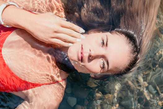 Side view a Young beautiful sensual woman in a mint long dress posing on a volcanic rock high above the sea during sunset. Girl on the nature on overcast sky background. Fashion photo