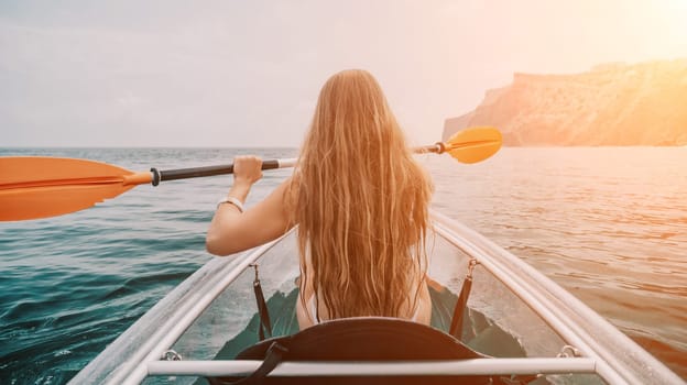 Woman in kayak back view. Happy young woman with long hair floating in transparent kayak on the crystal clear sea. Summer holiday vacation and cheerful female people having fun on the boat.