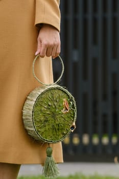 Round green handbag with a flower decor in the girl's hand.