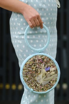 Round blue handbag with a decor of flowers in the girl's hand.