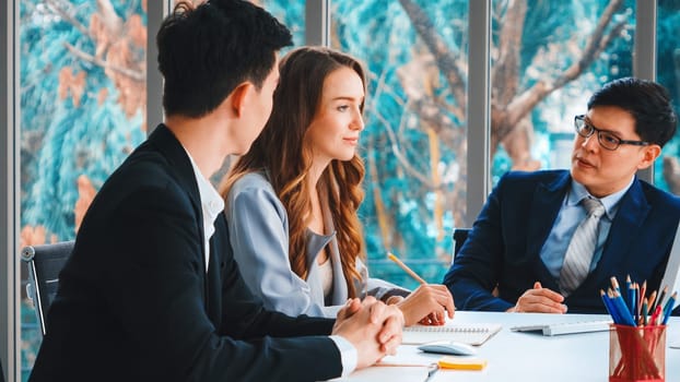 Smart businessman and businesswoman talking discussion in group meeting at office table in a modern office interior. Business collaboration strategic planning and brainstorming of coworkers. Jivy