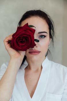 brunette woman closed her eye with a red rose flower