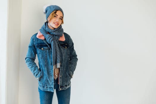 a woman in winter clothes in a hat stands in a bright room