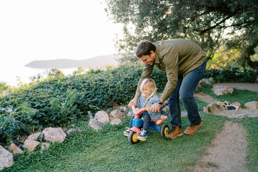 Dad is carrying a little girl pedaling on a bicycle. High quality photo