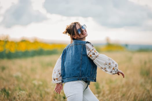 Smiling attractive hippy woman on nature background. Young lady in white embroidery shirt, denim waistcoat. Summer fashion, hipster, ethno, folk lifestyle.