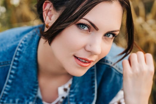 Smiling attractive hippy woman on nature background. Young lady in white embroidery shirt, denim waistcoat. Summer fashion, hipster, ethno, folk lifestyle.