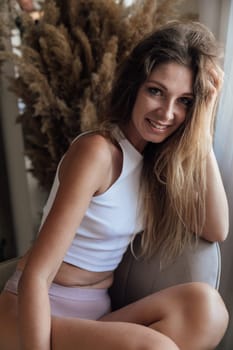 woman sits in a chair near a dry flower