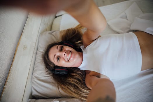 a woman in bed with headphones listening to music in bedroom room in the morning rest