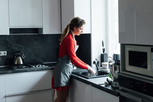 a woman cook in the kitchen washes dishes by window interior furniture