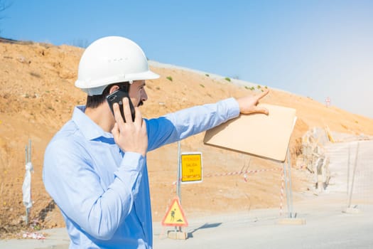 Construction man with white helmet working with phone. High quality photo