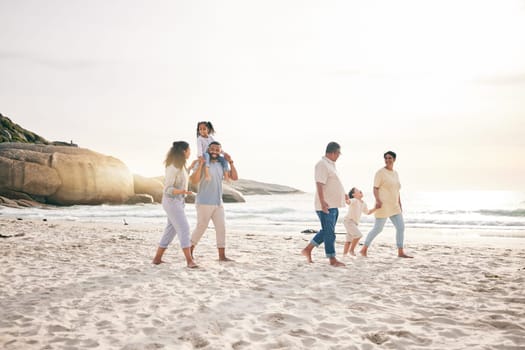 Holding hands, walking and big family at a beach for travel, vacation and fun in nature together. Freedom, parents and children relax with grandparents at the sea at sunset, trip or ocean holiday.