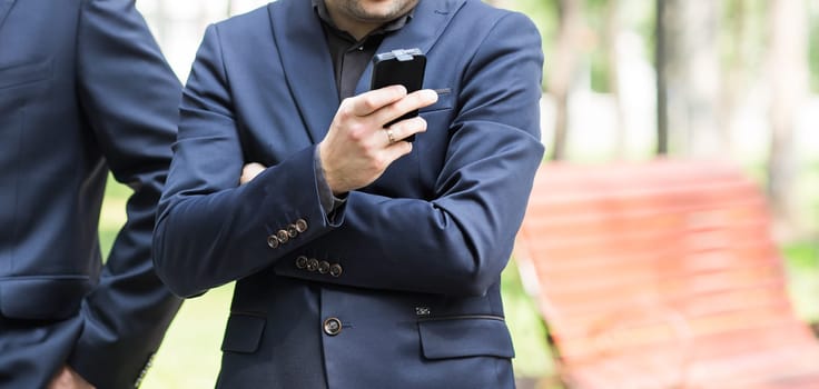 Young urban professional man using smart phone. Businessman holding mobile smartphone using app texting sms message.