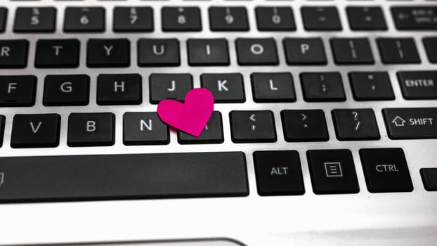 Heart shaped paper cut out on keyboard, love message and Valentine`s day concept.