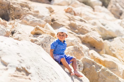 Smiling boy sitting on the rock outdoors