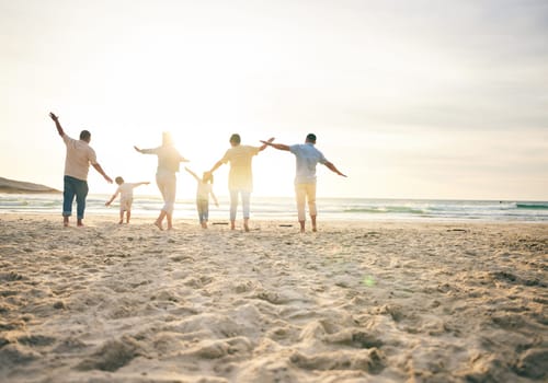 Family, generations and back view on the beach, travel and tropical vacation with freedom and sunshine. People outdoor, grandparents and parents with young kids, adventure and happiness in nature.