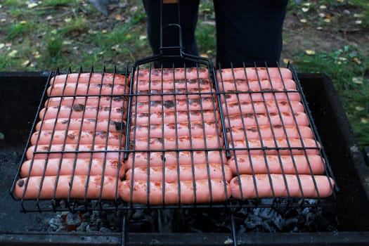 Photo sausages on the grill are fried on the grill. Outdoor recreation. Snack.