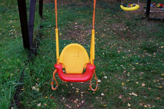 Photo baby plastic swing for toddlers. Children's playground. Country life. Walking with children.